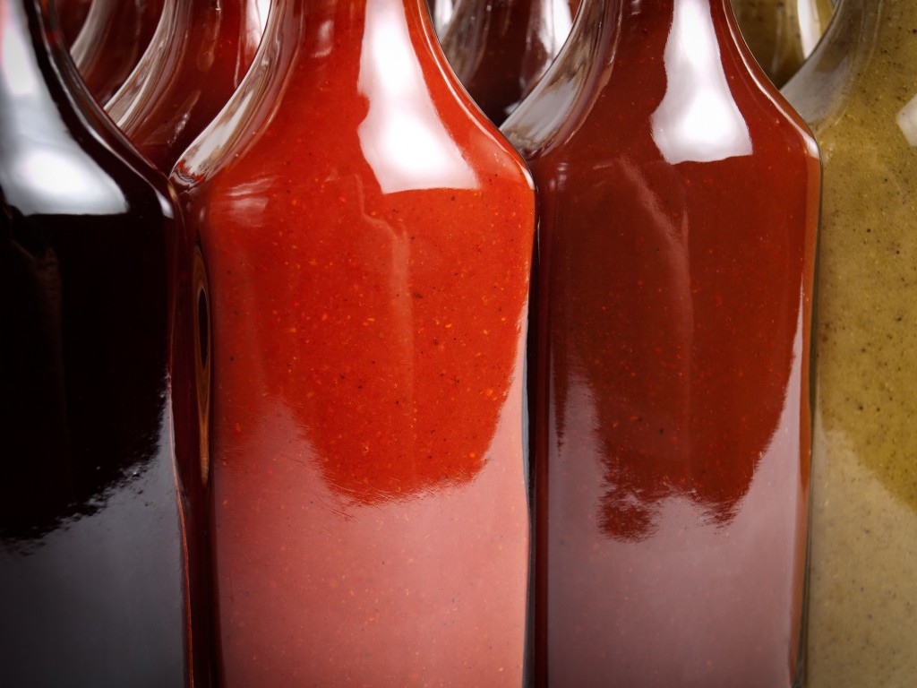 Closeup view of several glass bottles filled with various types of hot sauces.