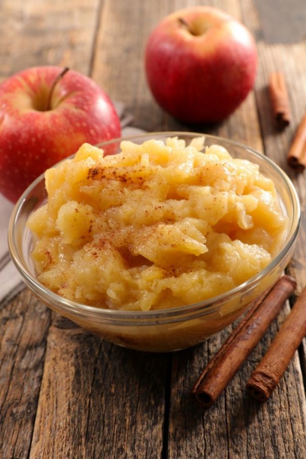 Fermented Apple Pear Sauce Bowl of applesauce on a wooden surface next to whole apples and cinnamon sticks