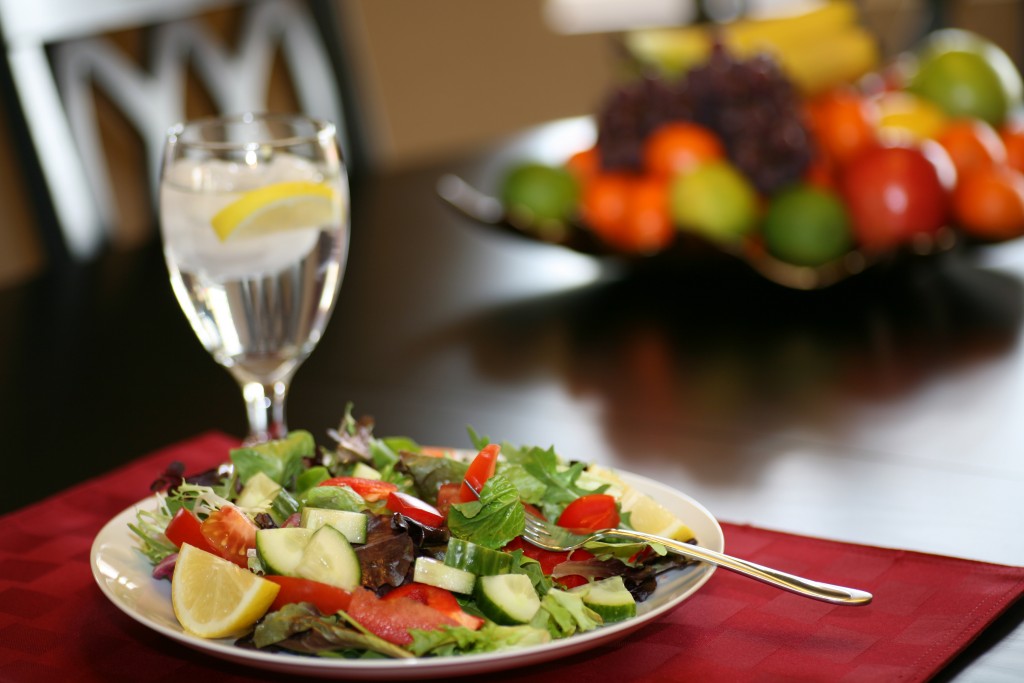 A Plate full of Organic Greens, Tomatoes, Cucumbers, Red Bell Peppers, and Fresh Lemon