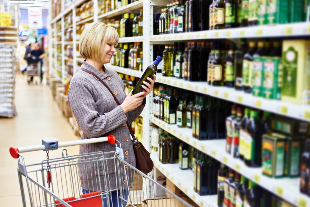 Woman reading the label on a bottle of olive oil in the store